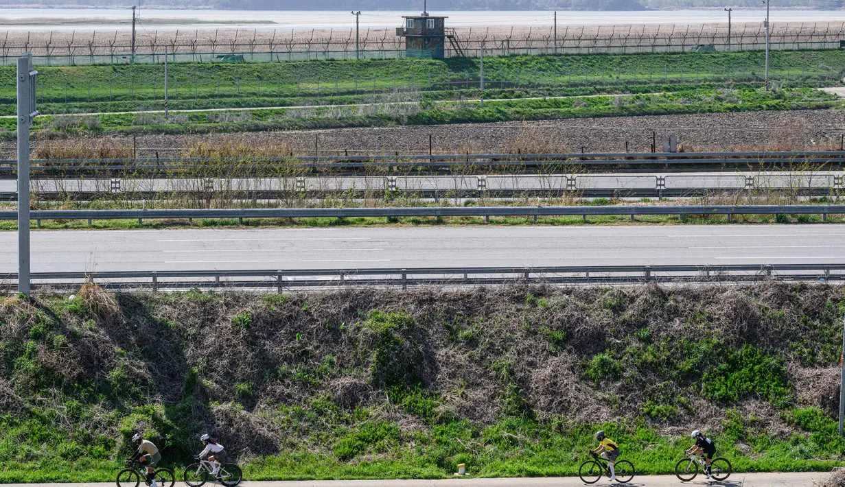 Dalam foto yang diambil pada tanggal 24 April 2025 ini memperlihatkan para pesepeda (bawah) terlihat dari halaman kafe Daonsoop, yang dibangun kurang dari dua kilometer dari perbatasan Korea Utara (latar belakang) di Paju, sebelah utara Seoul, Korea Selatan. (ANTHONY WALLACE/AFP)