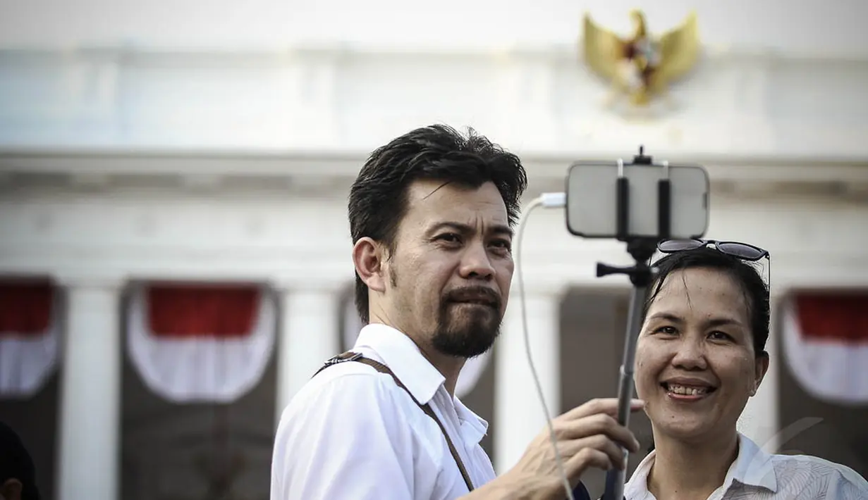 Sepasang warga terlihat tengah berselfie dengan latar belakang Istana Negara, Jakarta, (20/10/14). (Liputan6.com/Faizal Fanani)