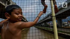 Anak-anak bermain dan berenang di aliran Kalimalang, Jakarta, Sabtu (15/2/2020). Cuaca yang tidak menentu membuat aliran air terkadang menjadi deras sehingga akan membahayakan keselamatan anak-anak saat bermain dan berenang. (merdeka.com/Imam Buhori)