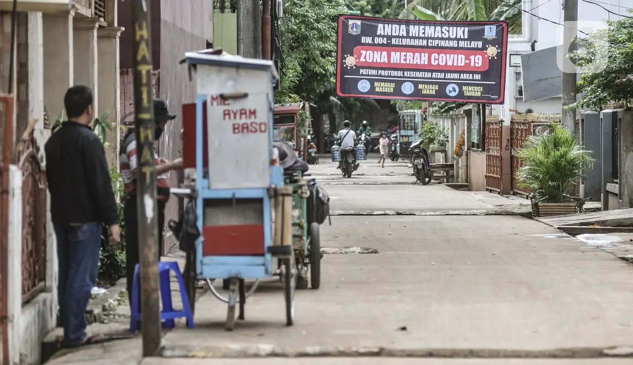 Aktivitas warga di salah satu gang yang masuk zona merah Covid-19 di RW 004, Cipinang Melayu, Jakarta, Rabu (27/1/2021). Pemprov DKI Jakarta mencatat sebanyak 54 rukun warga (RW) menjadi zona merah Covid-19 per 21 Januari 2021. (merdeka.com/Iqbal S Nugroho)