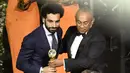 Mohamed Salah menerima trofi Pemain Terbaik Afrika 2017 dari Presiden CAF Ahmad Ahmad pada acara penghargaan tahunan Konfederasi Sepak Bola Afrika (CAF) di Ghana, Kamis (4/1). Salah membawa pulang penghargaan itu untuk pertama kali. (PIUS UTOMI EKPEI/AFP)