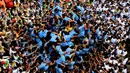 Pemuda India membentuk piramida manusia untuk memecahkan pot berisikan semacam susu dalam perayaan Festival Janmashtami di Mumbai, Senin (3/9). Para remaja mendaki ke tingkat paling atas tanpa alat keamanan sama sekali. (AP/Rafiq Maqbool)