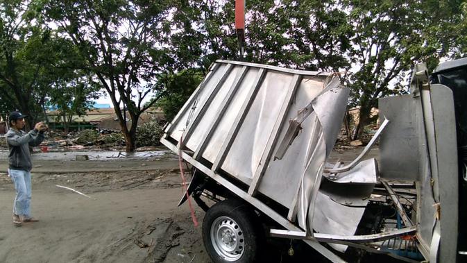 Seorang pria mengambil gambar kendaraan yang rusak akibat gempa dan tsunami di Palu, Sulawesi Tengah , Sabtu (29/9). Gelombang tsunami setinggi 1,5 meter yang menerjang Palu terjadi setelah gempa bumi mengguncang Palu dan Donggala. (AFP /OLA GONDRONK)