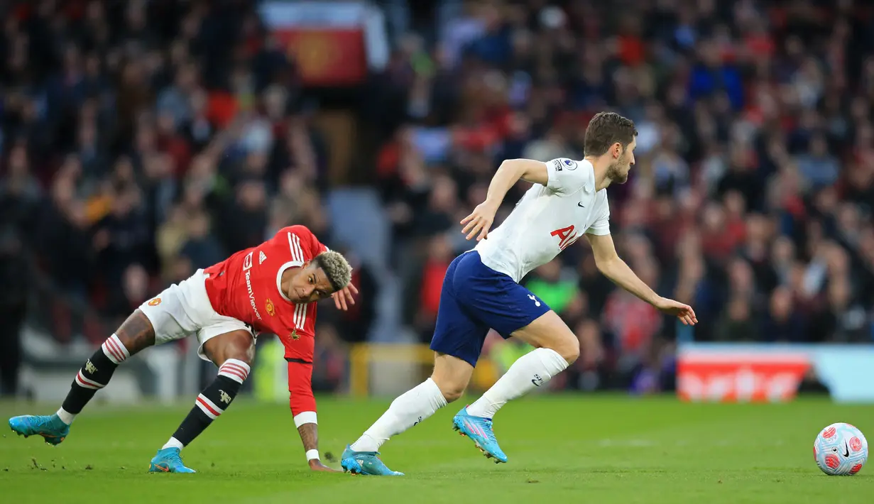 Bek Tottenham Hotspur Ben Davies (kanan) melarikan diri dari striker Manchester United (MU) Marcus Rashford (kiri) pada pekan ke-29 Liga Inggris di Old Trafford, Minggu (13/3/2022) dini hari WIB. Cristiano Ronaldo mencetak hattrick untuk membawa MU menang 3-2 atas Tottenham. (Lindsey Parnaby/AFP)