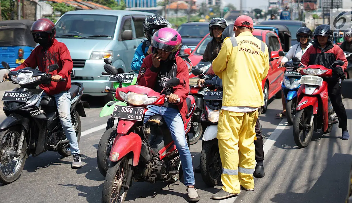 Petugas Sudin Bina Marga Jakarta Barat membagikan masker dan pasta gigi kepada pengendara motor di Jalan KS Tubun, Petamburan, Kamis (23/5/2019). Sisa gas air mata untuk membubarkan massa dalam kericuhan aksi 22 Mei masih terasa dan mengganggu aktvitas pengguna jalan (Liputan6.com/Immanuel Antonius)