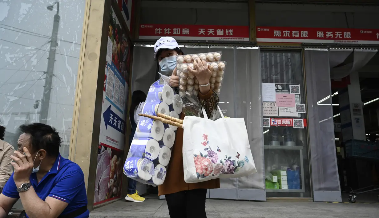 <p>Seorang wanita meninggalkan supermarket setelah membeli makanan dan perlengkapan rumah tangga di Beijing pada 25 April 2022. Kekhawatiran penguncian Covid memicu pembelian panik dan antrean panjang untuk pengujian massal di Beijing pada 25 April ketika otoritas China bergegas untuk membasmi wabah di ibu kota. (AFP/Noel Celis)</p>