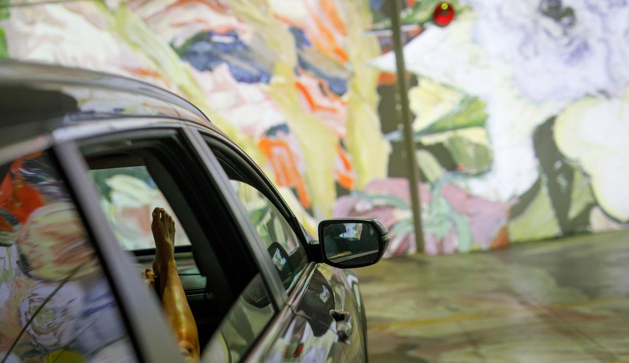Orang-orang duduk di mobil mereka menikmati pameran seni Vincent Van Gogh di Toronto, Ontario, Kanada pada 3 Juli 2020. Pameran seni di masa pandemi Covid-19 mendatangkan ide kreatif para penyelenggara kegiatan dengan memamerkan hasil karya seni lewat konsep drive-in. (Cole BURSTON/AFP)