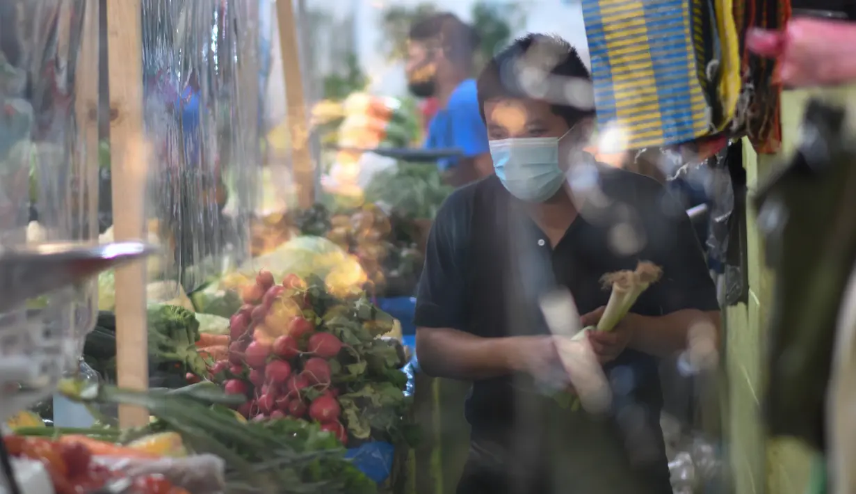 Pelanggan membeli sayuran di sebuah kios dengan sekat tirai pelindung plastik di pasar La Asuncion di Villa Nueva, Guatemala City pada 20 Juli 2020. Kios di pasar itu menggunakan tirai pelindung plastik untuk menjaga jarak fisik guna mengurangi resiko penyebaran virus Corona. (Johan ORDONEZ/AFP)