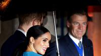 Meghan Markle memegang lengan Pangeran Harry yang memayunginya saat tiba di Endeavour Fund Awards, London, Inggris, Kamis (5/3/2020). Meghan Markle memilih tampil dengan dress rancangan Victoria Beckham. (AP Photo/Kirsty Wigglesworth)