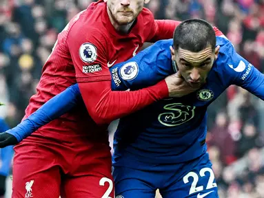 Pemain Chelsea, Hakim Ziyech, diadang pemain Liverpool,  Andrew Robertson, pada laga Liga Inggris di Stadion Anfield (21/1/2023). Impian Hakim Ziyech bermain bersama Lionel Messi, Neymar, Kylian Mbappe, dan sahabat baiknya Achraf Hakimi, gagal total. Transfernya sebagai pemain pinjaman ke PSG batal di akhir-akhir bursa transfer bulan Januari 2023 karena The Blues salah mengirim dokumen. (AFP/Paul Ellis)