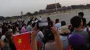 Warga mengambil foto setelah upacara pengibaran bendera saat fajar setelah kematian mantan perdana menteri China Li Peng di Lapangan Tiananmen Beijing (24/7/2019). Li Peng meninggal dunia akibat menderita kanker kandung kemih. (AFP Photo/Greg Baker)