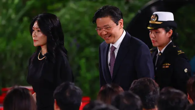 Perdana Menteri Singapura yang baru, Lawrence Wong (tengah) berjalan di samping istrinya Loo Tze Lui (kiri) pada upacara pelantikan di Istana di Singapura pada 15 Mei 2024. (Dok: Edgar Su / POOL/ AFP)