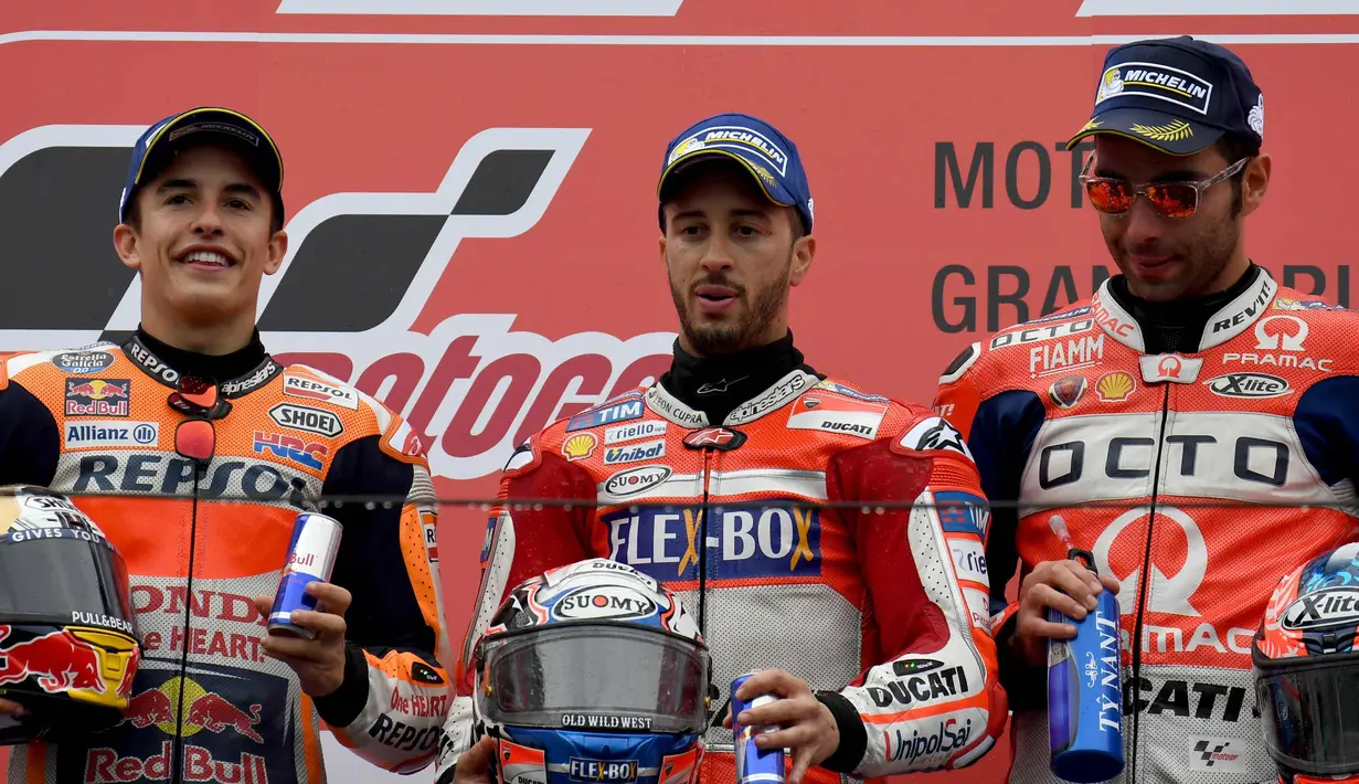 Pembalap Ducati, Andrea Dovizioso (tengah) berpose diatas podium dengan pembalap Honda Marc Marquez dan Danilo Petrucci usai memenangi MotoGP Jepang di sirkuit Motegi (15/10). (AFP Photo/Toshifumi Kitamura)