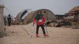 Bocah Suriah, Maya Merhi berjalan dengan kaki prostetik dibantu tongkat kruk di kamp Serjilla, 9 Desember 2018. Gadis 8 tahun itu kini bisa berjalan menggunakan kaki prostetik baru atau kaki buatan setelah menjalani perawatan di Turki. (Aaref WATAD/AFP)
