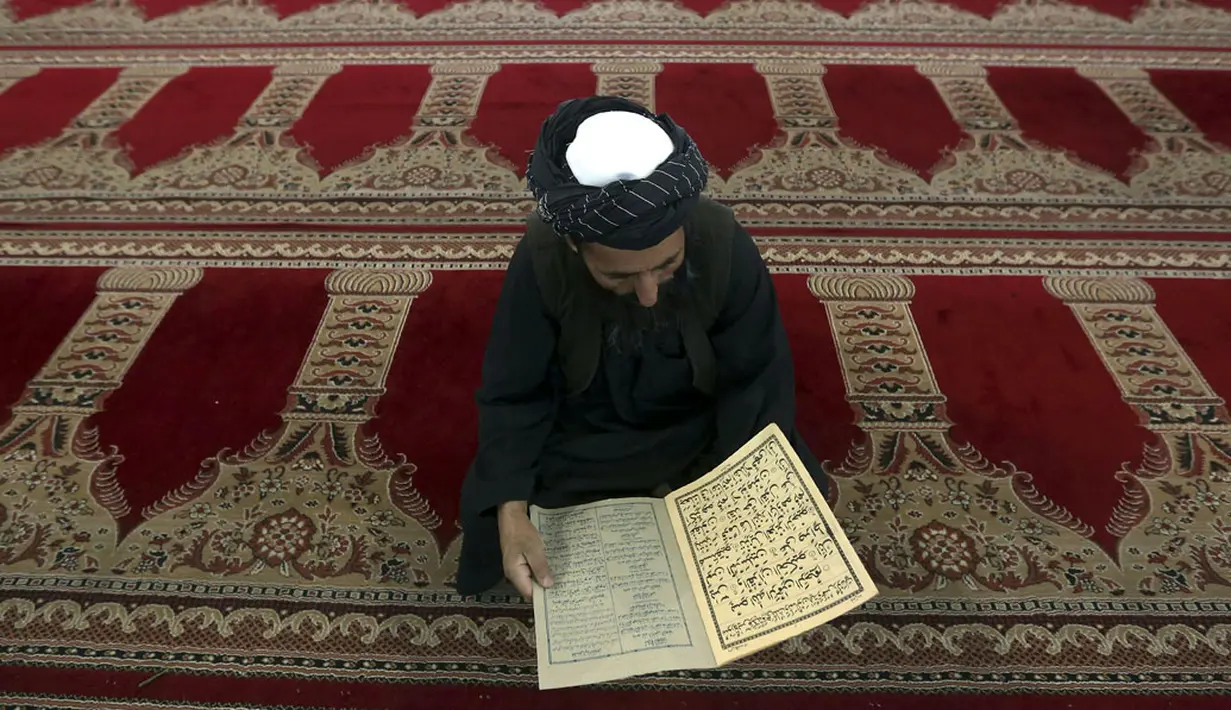 Salah satu umat muslim di Kabul, Afghanistan, membaca kitab suci Al Qur'an di hari pertama Ramadan, (29/6/2014). (REUTERS/Omar Sobhani)