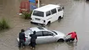 Warga mendorong sebuah mobil yang mogok di jalan banjir akibat hujan deras di Beirut, Lebanon (9/12/2019). Hujan deras membuat sejumlah rumah dan kendaraan di Lebanon terendam banjir dan melumpuhkan daerah-daerah dari ibukota Beirut, Lebanon. (AFP Photo/Anwar Amro)