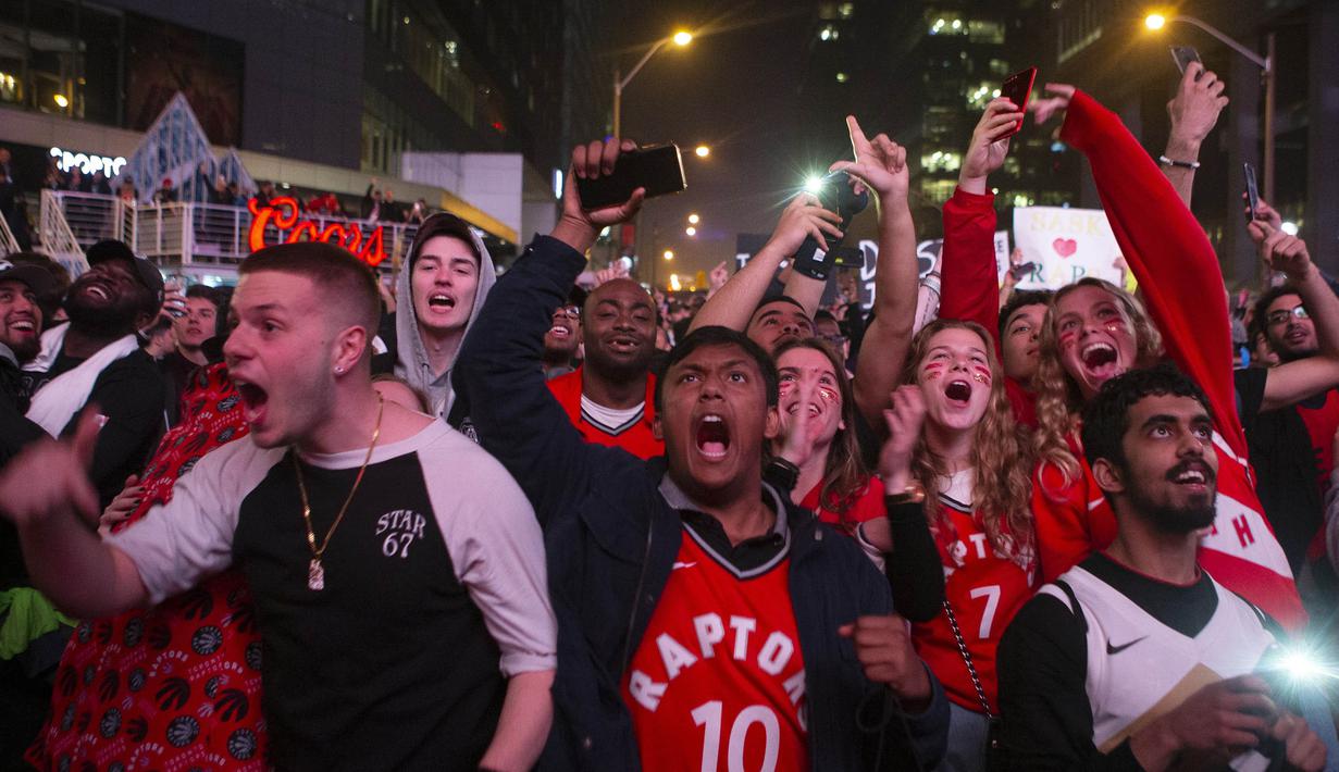 Suporter Toronto Raptors merayakan kemenangan atas Milwaukee Bucks pada NBA Final Wilayah Timur di Scotiabank Arena, Toronto, Sabtu (25/5). Raptors menang 4-2 atas Bucks. (AP/Chris Young)