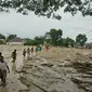 Penduduk desa berjalan melalui daerah banjir di desa Radda di Kabupaten Luwu Utara, Sulawesi Selatan (14/7/2020). Akibat musibah banjir bandang ini setidaknya sekitar 15 orang tewas dan belasan lainnya dinyatakan hilang. (AP Photo)