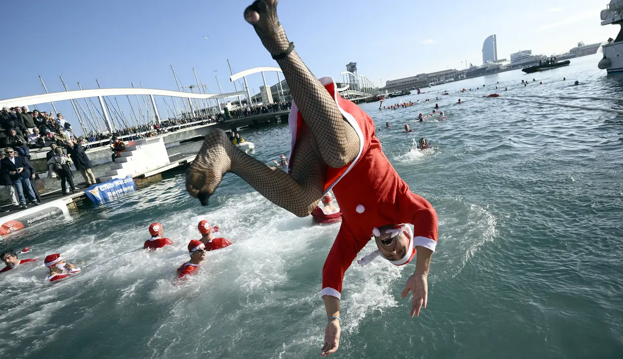 Seorang peserta mengenakan kostum Sinterklas terjun dengan cara salto dalam perlombaan renang bertajuk Copa Nadal (Piala Natal) edisi ke-115 yang berlangsung di Port Vell, Barcelona, Spanyol, Rabu (25/12/2024). Ajang tersebut diikuti oleh 450 peserta dengan jarak renang sejauh 200 meter. (AFP/Josep Lago)