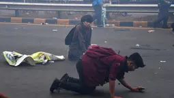 Mahasiswa tersungkur saat mencoba melarikan diri dari tembakan gas air mata aparat kepolisian dalam demonstrasi menolak pengesahan RUU KUHP dan revisi UU KPK di depan Gedung DPR, Jakarta, Selasa (24/9/2019). Sejumlah mahasiswa tumbang setelah polisi menembakkan gas air mata. (ADEK BERRY/AFP)