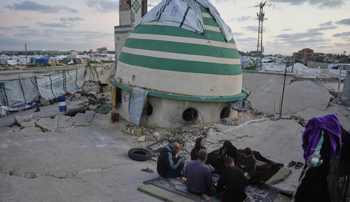 Keluarga Suleiman berbuka puasa di bulan suci Ramadan di samping reruntuhan masjid, tempat mereka saat ini berlindung di Deir al-Balah, Jalur Gaza, Jumat 6 Maret 2026. Di tengah kesulitan, keluarga Suleiman di Deir al-Balah, Jalur Gaza, berkumpul untuk menikmati momen berbuka puasa bersama. (AP Photo/Abdel Kareem Hana)
