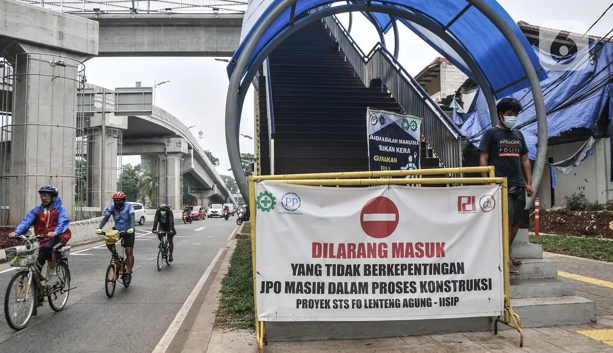 Pejalan kaki melintasi banner 'Dilarang Masuk' yang terpasang di pintu masuk JPO Flyover Tapal Kuda Lenteng Agung, Jakarta, Minggu (29/8/21) Diketahui JPO ini telah rampung sejak awal Agustus namun belum tahu kapan akan diresmikan Gubernur DKI Jakarta Anies Baswedan (merdeka.com/Iqbal S Nugroho)