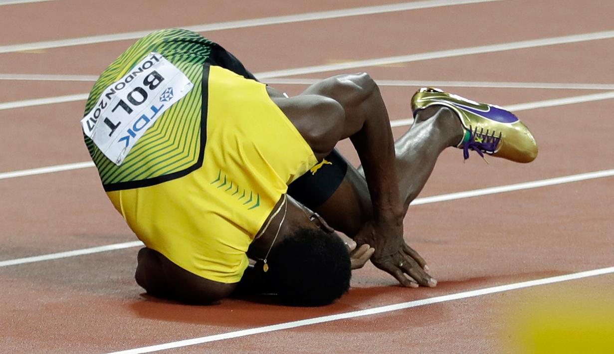 Pelari asal Jamaika, Usain Bolt terkapar di lintasan setelah terjatuh di final 4x100 meter pada Kejuaraan Dunia Atletik di London, Sabtu (12/8). Bolt sempat tertatih-tatih sebelum akhirnya jatuh dan gagal melanjutkan lomba. (AP/Matthias Schrader)