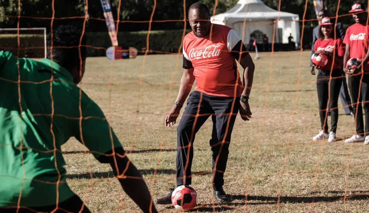 Presiden Kenya Uhuru Kenyatta bermain bola selama tur trofi Piala Dunia FIFA Tour di State House di Nairobi (26/2). Trofi tersebut melakukan tur internasional untuk mempromosikan turnamen yang dimulai pada bulan Juni di Rusia. (AFP Photo/Yasuyoshi Chiba)