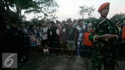 Petugas berjaga di sekitar lokasi helikopter jatuh yang sudah di tutup terpal di Dusun Kowang, Sleman (8/7). Heli jatuh setelah melakukan penerbangan dari Solo menuju Yogyakarta. (Liputan6.com/Boy Harjanto)