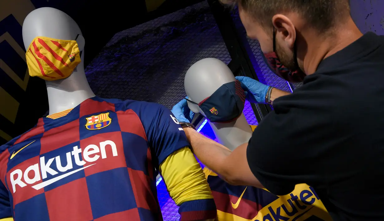 Penjaga toko memasang masker berlogo Barcelona ke Manekin di Toko Asesoris Barcelona, Senin (25/5/2020). Di tengah pandemi virus Corona, Barcelona menjual masker dengan harga 18 euro atau sekitar Rp 291 ribu. (AFP/Lluis Gene)