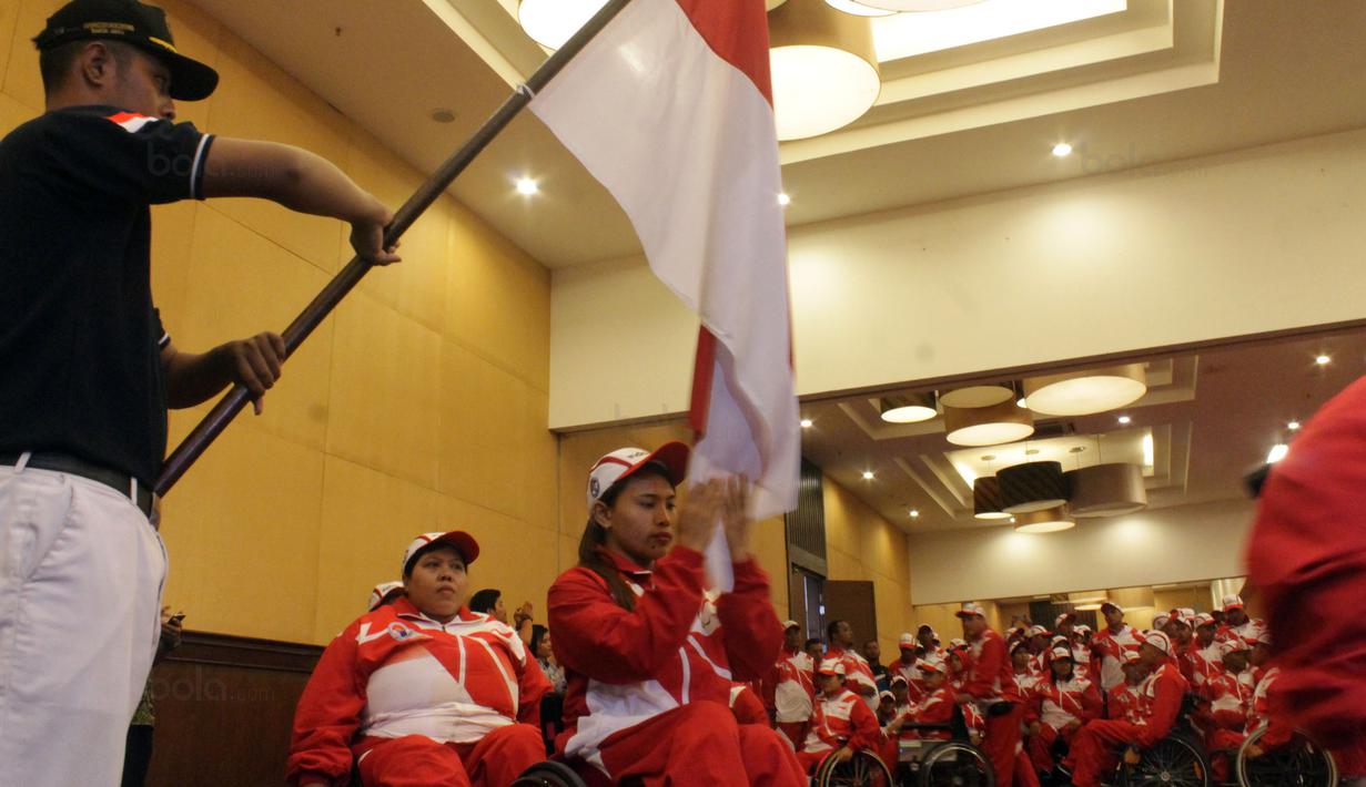 Atlet angkat berat Indonesia, Ni Nengah Widiasih mencium bendera Merah Putih saat pelepasan kontingen Indonesia ke ASEAN Paragames  2017 di Hotel Lorin Solo, Selasa (12/9/2017). Indonesia diharapkan meraih juara umum di APG. (Bola.com/Ronald Seger)