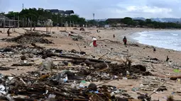 Sampah plastik maupun batang kayu mengotori pantai berpasir putih ini. (SONNY TUMBELAKA/AFP)