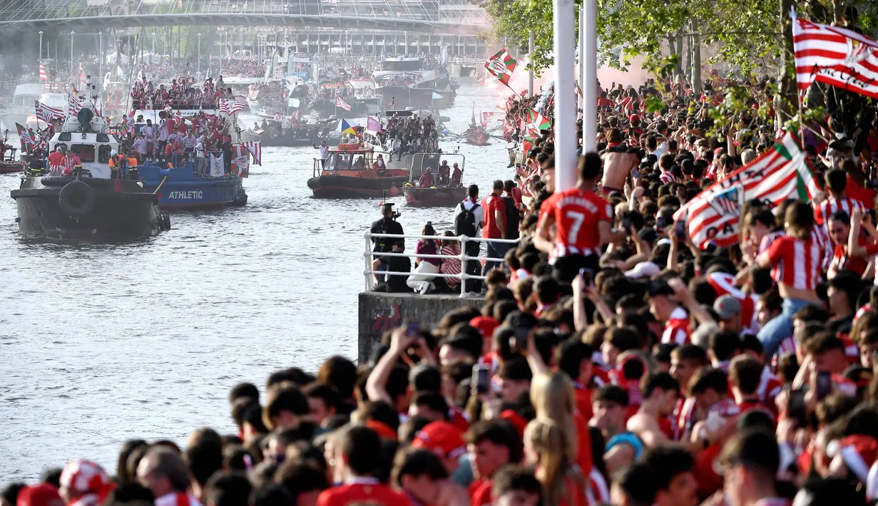 Ribuan suporter menyambut pemain Athletic Bilbao yang melakukan pawai perayaan juara Copa del Rey dengan menyusuri Sungai Nervion, Bilbao, Jumat (12/4/2024). Athletic Bilbao merayakan trofi besar pertama sejak selama 40 tahun puasa gelar.  (AFP/Ander Gillenea)