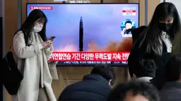 Seorang wanita berjalan di depan layar TV yang menunjukkan gambar file peluncuran rudal Korea Utara saat program berita di Stasiun Kereta Api Seoul, Seoul, Korea Selatan, Selasa (14/3/2023). Korea Utara melakukan uji coba menembakkan dua rudal balistik jarak pendek ke arah perairan timurnya pada hari Selasa dalam unjuk kekuatan kedua Pyongyang minggu ini, sehari setelah dimulainya latihan militer AS-Korea Selatan yang dipandang Korea Utara sebagai latihan invasi. (AP Photo/Ahn Young-joon)