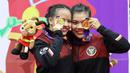 Pesilat Indonesia Riska Hermawan (kiri) dan Ririn Rinasih menunjukkan medali emas usai menjuarai nomor Seni Ganda Wanita Pencak Silat Sea Games 2021 Vietnam di Bac tu Liem Sport Center, Hanoi, Rabu (11/5/2022). (Bola.com/Ikhwan Yanuar)