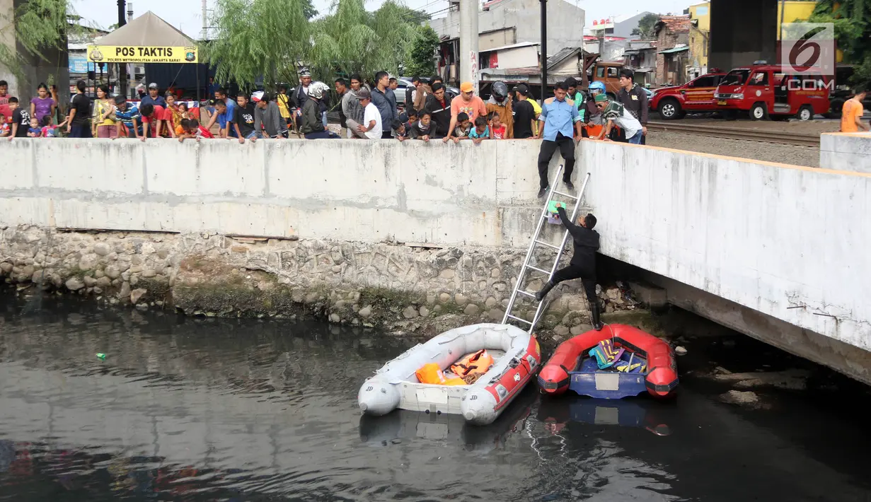 Warga melihat petugas melakukan pencarian buaya di Kali Grogol, Jakarta Barat, Jumat (29/6). Pencarian buaya sempat membuahkan hasil pada hari ketiga pencarian, namun kondisi teknis lapangan membuat predator itu kembali lepas. (Liputan6.com/Arya Manggala)
