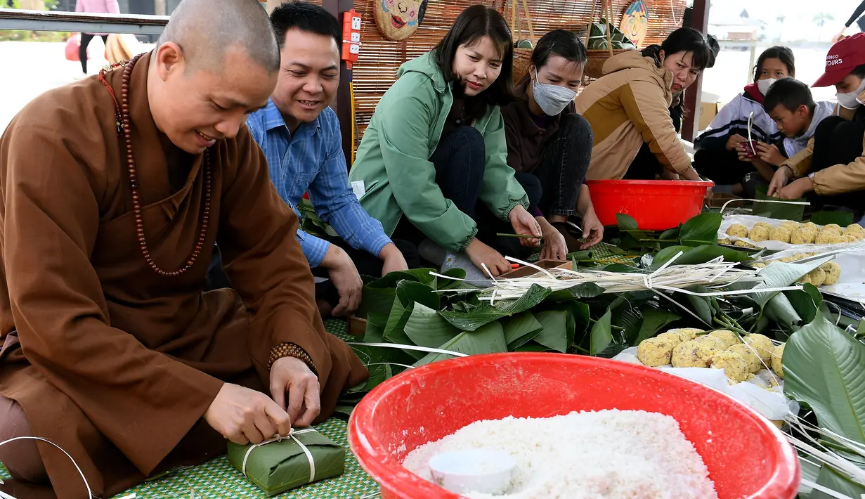 Orang-orang menyiapkan "Banh Chung" atau kue beras tradisional Vietnam untuk amal, menjelang Tahun Baru Imlek atau festival Tet di Pagoda Tam Chuc di provinsi Ha Nam (7/1/2023). Banh Chung adalah kelezatan khas Vietnam yang terbuat dari ketan, daging babi, dan kacang hijau yang dibungkus dengan daun pisang dan dimasak selama 10 jam. (AFP/Nhac Nguyen)