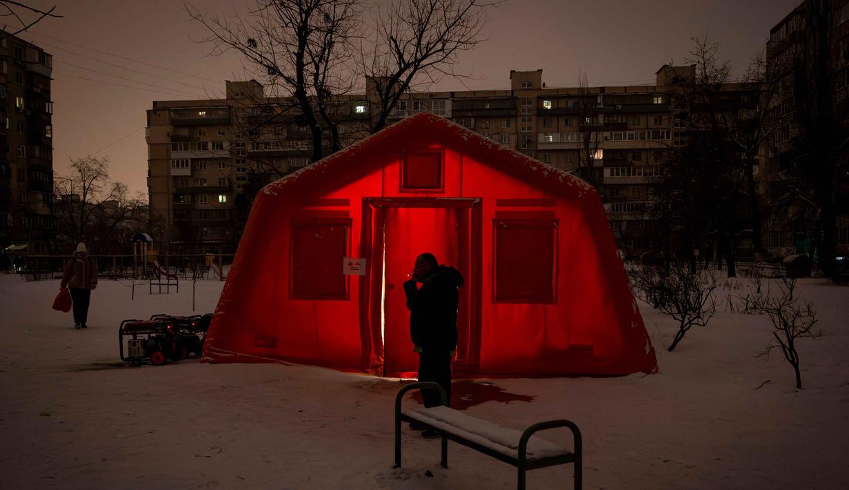 Seorang pria berada di luar tenda darurat tempat orang-orang dapat menghangatkan diri setelah serangan udara rutin Rusia terhadap fasilitas energi negara itu di tengah musim dingin, Kyiv, Ukraina, Selasa 13 Januari 2026. Militer Rusia kembali meluncurkan serangan udara besar-besaran ke Ukraina, Selasa (13/1/2026). (AP Photo/Danyil Bashakov)
