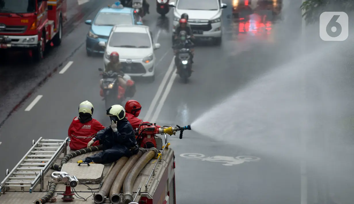 Petugas pemadam kebakaran (Damkar) melakukan penyemprotan cairan disinfektan di sepanjang jalan Thamrin-Sudirman, Jakarta, Sabtu (28/3/2020). Penyemprotan menggunakan mobil pemadam kebakaran tersebut bertujuan untuk mengantisipasi penyebaran Virus Corona (COVID-19). (merdeka.com/Imam Buhori)
