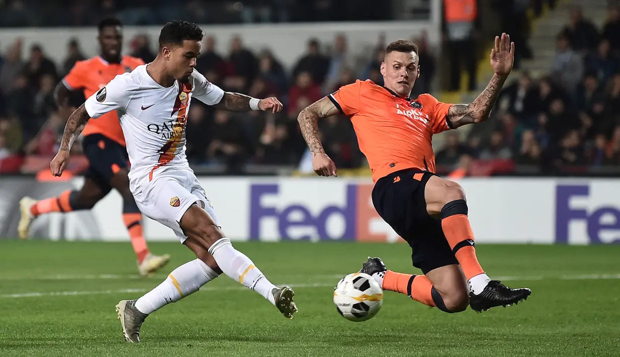 Winger AS Roma, Justin Kluivert, menendang bola ke gawang dibayangi pemain Istanbul Basaksehir pada laga kelima Grup J Liga Europa 2019-2020 di stadion Fatih Terim, Kamis (28/11/2019). AS Roma menang meyakinkan dengan skor 3-0.  (Ozan KOSE / AFP)