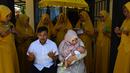 Seorang ibu mengendong bayinya saat ritual 'peutron tanoh aneuk' (turun tanah anak) di Banda Aceh, Aceh, Senin (15/7/2019). Ritual turun tanah anak telah menjadi tradisi sakral bagi masyarakat Aceh yang dilaksanakan pada saat bayi berusia 44 hari. (CHAIDEER MAHYUDDIN / AFP)