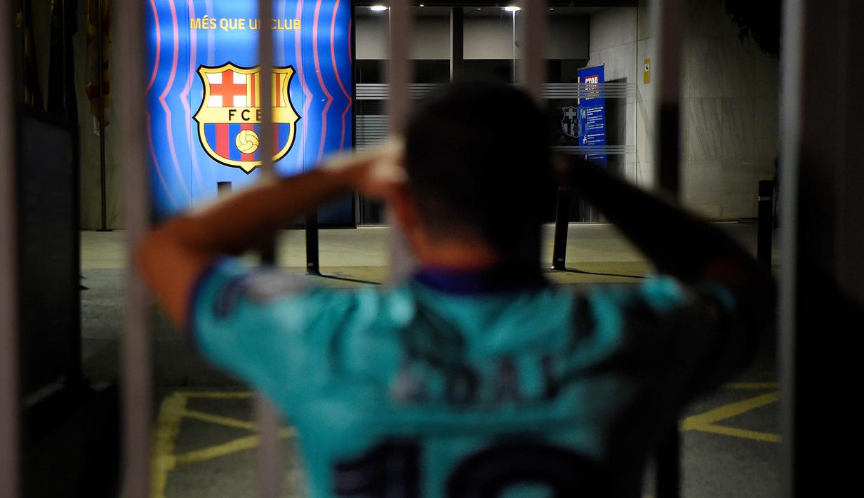 Suporter memgang kepala saat mengikuti protes di depan kantor Barcelona, Selasa (25/8/2020). Aksi tersebut merupakan respon fans atas kabar Lionel Messi yang akan meninggalkan Camp Nou pada musim panas ini. (AFP/Pau Barrena)