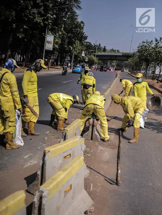 Petugas Dinas Bina Marga DKI Jakarta memperbaiki separator busway di kawasan Jalan Gatot Subroto, Jakarta, Selasa (1/10/2019). Separator busway dirusak massa saat terjadi bentrok antara polisi dengan demonstran di kawasan tersebut. (Liputan6.com/Faizal Fanani)