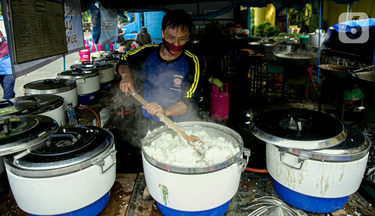 Petugas Taruna Siaga Bencana (Tagana) memasak nasi di Dapur Umum Kementerian Sosial di GOR Otista, Jakarta, Minggu (21/2/2021). Dalam sehari, petugas menyiapkan hingga 6.000 paket nasi kotak yang didistribusikan ke 11 kelurahan terdampak banjir. (Liputan6.com/Faizal Fanani)