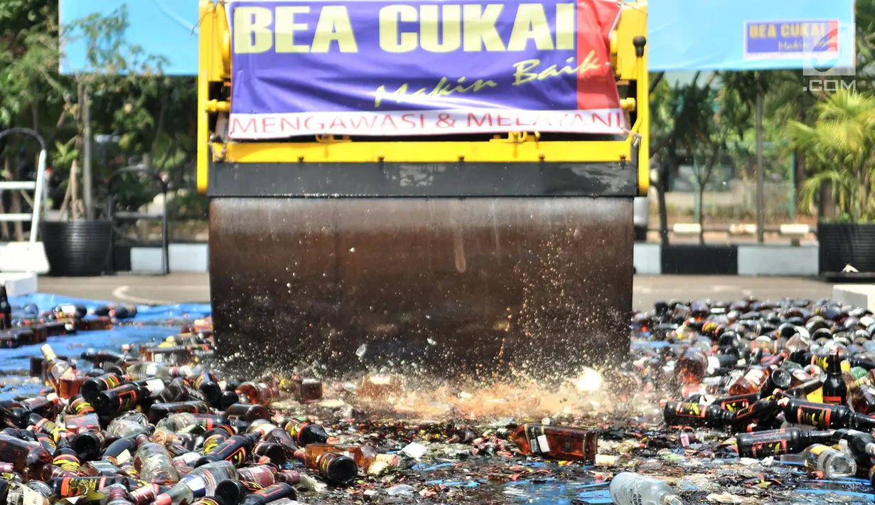 Buldozer melindas ribuan botol minuman keras ilegal saat dimusnahkan di Kantor Bea Cukai Marunda, Jakarta, Selasa (2/10). Sebanyak 2.245 minuman keras ilegal dimusnahkan. (Merdeka.com/Iqbal Nugroho)