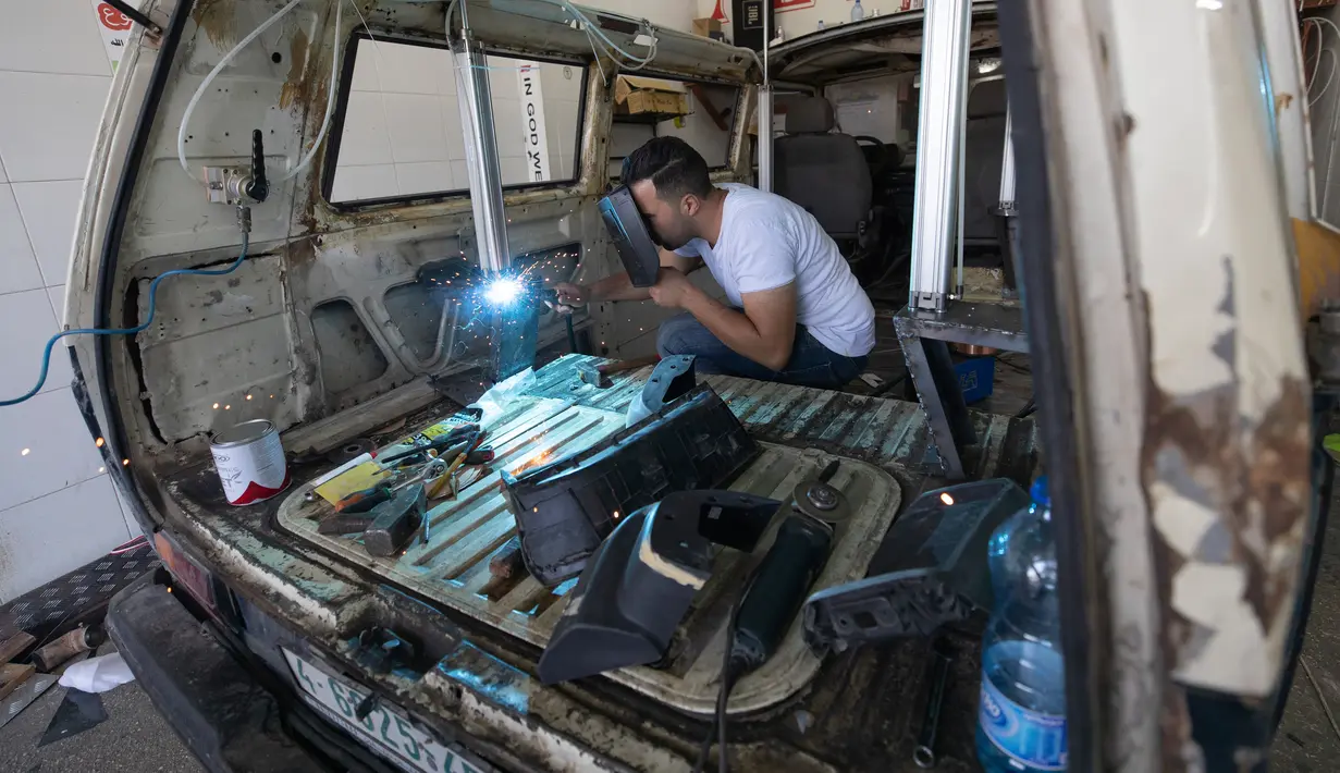 Seorang tukang las mengubah van menjadi food truck di sebuah bengkel di kota Ramallah, Tepi Barat, Selasa, 22 September 2020. Dengan sebagian besar restoran tutup karena pembatasan COVID-19, food truck memungkinkan pengusaha Palestina untuk menemukan cara tetap bekerja. (AP Photo/Nasser Nasser)