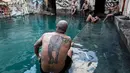 Seorang pria dengan tato macan tutul duduk bersantai di kolam air panas di ujung selatan Dataran Tinggi Golan yang dianeksasi Israel, 1 Maret 2019. Kolam dengan air panas itu berasal dari aliran pipa pengeboran di Lembah Hula. (MENAHEM KAHANA/AFP)