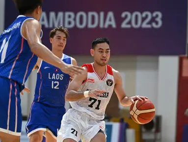 Pebasket Indonesia, Widyanta Putra Teja (kanan) berlari dengan bola melewati pemain Laos Phouthong Labouphieng babak penyisihan Grup B SEA Games 2023 di Phnom Penh, Kamboja, Rabu (10/5/2023). (Photo by TANG CHHIN SOTHY / AFP)