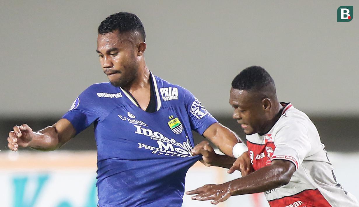 Madura United yang tak mau tampil mengecewakan terus menerus menekan Persib Bandung. Saling tarik baju antara Ardi Idrus dan David Laly pun tak terelakkan.  (Bola.com/Bagaskara Lazuardi)