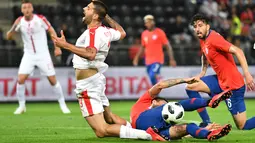 Pemain Serbia, Aleksandar Mitrovic (kiri) jatuh saat berebut bola dengan pemain Chili, Erick Pulgar pada laga uji coba di Merkur Arena, Graz, Austria, (4/6/2018).  Serbia kalah dari Chili 0-1. (AFP/Joe Klamar)